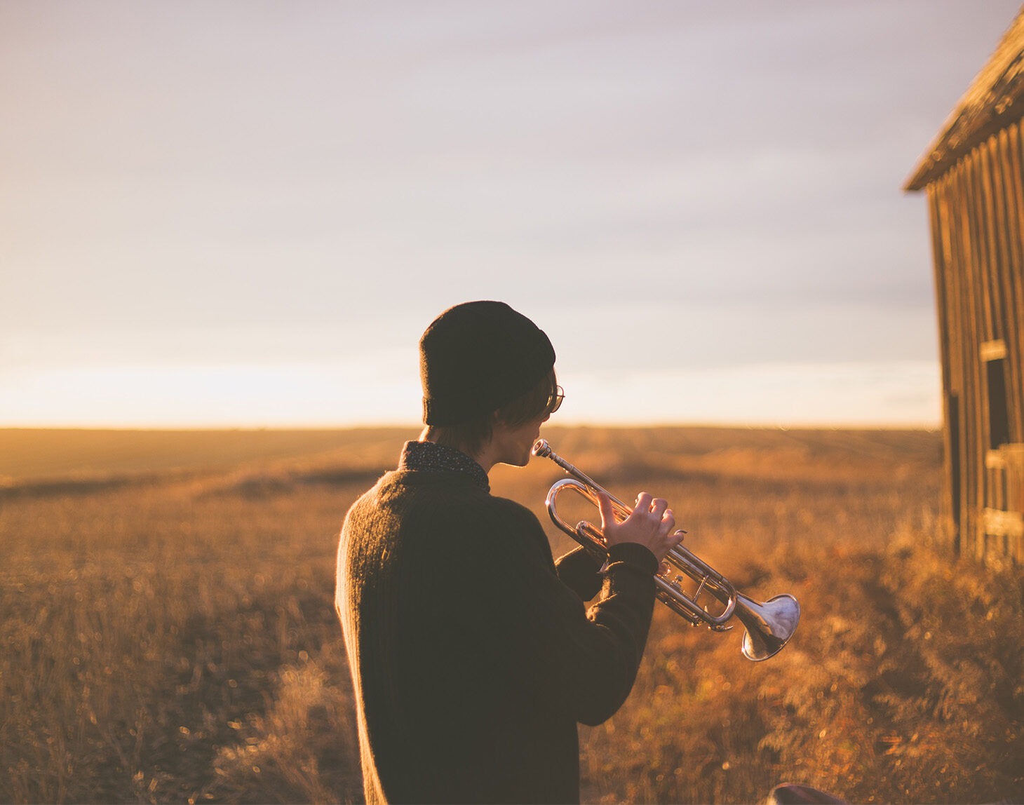 guy playing trumpet in field